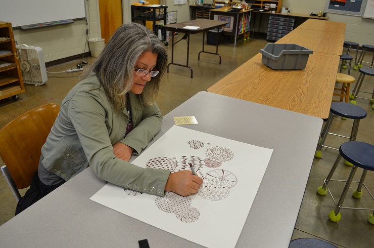 Ms. Julie Richard, art teacher here, continues work on another of her mesmerizing masterpieces during our lunchtime chat.